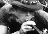 Egy Saigontól 80 kilométerre lévő tisztáson kialakított állásban amerikai katonák egy általuk Ralph névre keresztelt sörétes puska csövéből szívnak marihuánafüstöt, 1970.