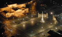 A parkoló gépkocsikkal együtt is szép látvány  madártávlatból, esti díszkivilágításban a díszburkolattal ellátott tér (Civertan Grafikai Stúdió / wikipédia)
