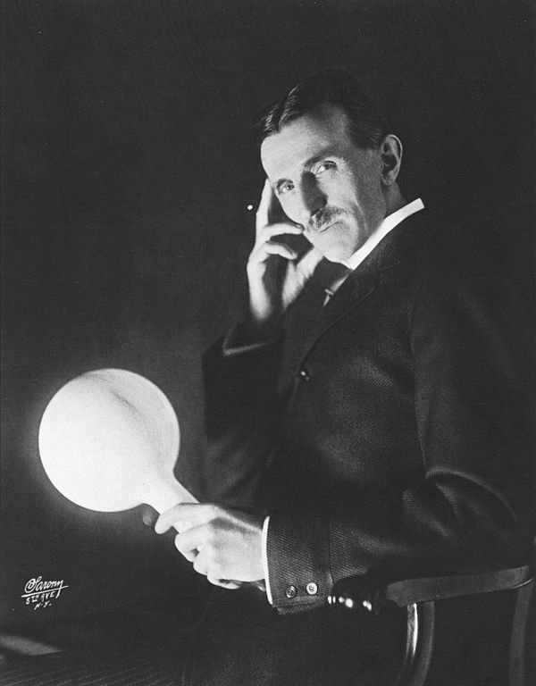 Nikola Tesla egy villanykörtével, ami a generátortól több méterre is világít.