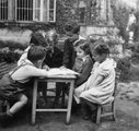 vábhegy, a Gyöngyvirág utca 12-14. kertje. A szomszéd gyerekeknek és testvérének magyaráz a szemben ülő ifjú Nádas Péter késöbbi író, 1954