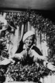 Bette Davis, 1930 – a legendásan igéző tekintetű színésznő szőrmeszegélyű sapkát és köpenyt visel, akárcsak maga a Télapóné, miközben egy óriási koszorú veszi körül egy karácsonyi fotózáson.