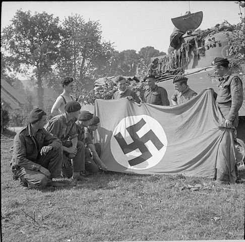 Egy Sherman tank legénysége az általuk zsákmányolt horogkeresztes zászlóval